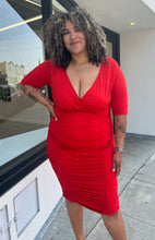 Load image into Gallery viewer, Front view of a size 3X Poseshe vibrant red ruched v-neck bodycon midi dress with three-quarter length sleevesl on a size 16/18 model. The photo is taken outside in natural lighting.
