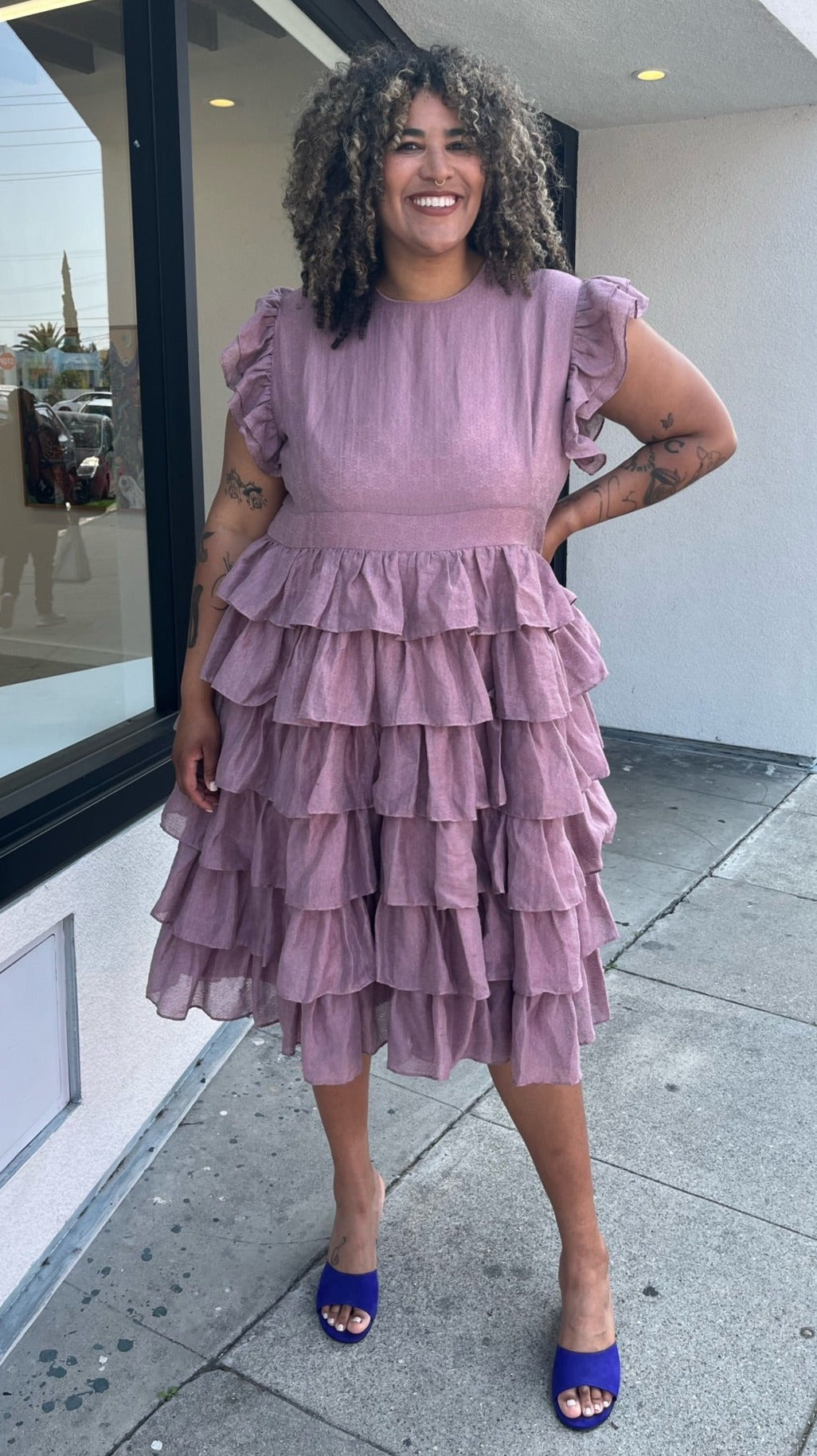 Full-body front view of a size 3X JessaKae mauve ruffle-tiered midi dress with burnout eyelet pattern and high neckline styled with bright purple heels on a size 16/18 model.