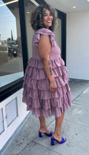 Load image into Gallery viewer, Full-body side view of a size 3X JessaKae mauve ruffle-tiered midi dress with burnout eyelet pattern and high neckline styled with bright purple heels on a size 16/18 model.
