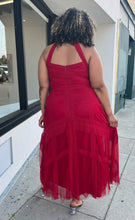 Load image into Gallery viewer, Full-body back view of a size 20 City Chic red lace and mesh halter-style gown with a tan mesh bust panel styled with black and clear heels on a size 16/18 model. The photo is taken outside in natural lighting.
