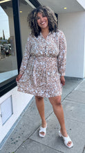 Load image into Gallery viewer, Full-body front view of a size 1/2X Brenin Newport vintage tan and white sketched floral collared a-line dress with a fabric belt styled with white heels on a size 16/18 model. The photo is taken outside in natural lighting.

