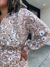 Load image into Gallery viewer, Close up view of the tan and white sketched floral pattern of a size 1/2X Brenin Newport vintage tan and white sketched floral collared a-line dress with a fabric belt on a size 16/18 model. The photo is taken outside in natural lighting.
