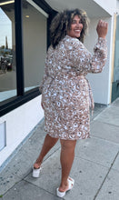 Load image into Gallery viewer, Full-body back view of a size 1/2X Brenin Newport vintage tan and white sketched floral collared a-line dress with a fabric belt styled with white heels on a size 16/18 model. The photo is taken outside in natural lighting.
