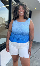 Load image into Gallery viewer, Front view of a size 1/2X light blue to dark blue ombre popcorn-style tank top styled over some cream denim shorts on a size 16/18 model. The photo is taken outside in natural lighting.
