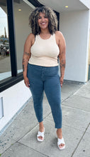 Load image into Gallery viewer, Full-body front view of a pair of size XXXL Knix slate blue tapered drawstring pants styled with a cream tank and white heels on a size 16/18 model. The photo is taken outside in natural lighting.
