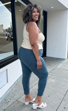 Load image into Gallery viewer, Full-body side view of a pair of size XXXL Knix slate blue tapered drawstring pants styled with a cream tank and white heels on a size 16/18 model. The photo is taken outside in natural lighting.
