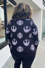 Load image into Gallery viewer, Back view of a size 2 Her Universal black and gray Star Wars Jedi and Rebel Alliance symbol sweater styled with black distressed jeans on a size 16/18 model. The photo is taken outside in natural lighting.
