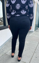 Load image into Gallery viewer, Back view of a pair of size 18 Torrid black distressed skinny jeans styled with a black and gray sweater and black loafers on a size 16/18 model. The photo is taken outside in natural lighting.
