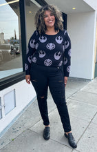 Load image into Gallery viewer, Full-body front view of a size 2 Her Universal black and gray Star Wars Jedi and Rebel Alliance symbol sweater styled with black distressed jeans on a size 16/18 model. The photo is taken outside in natural lighting.
