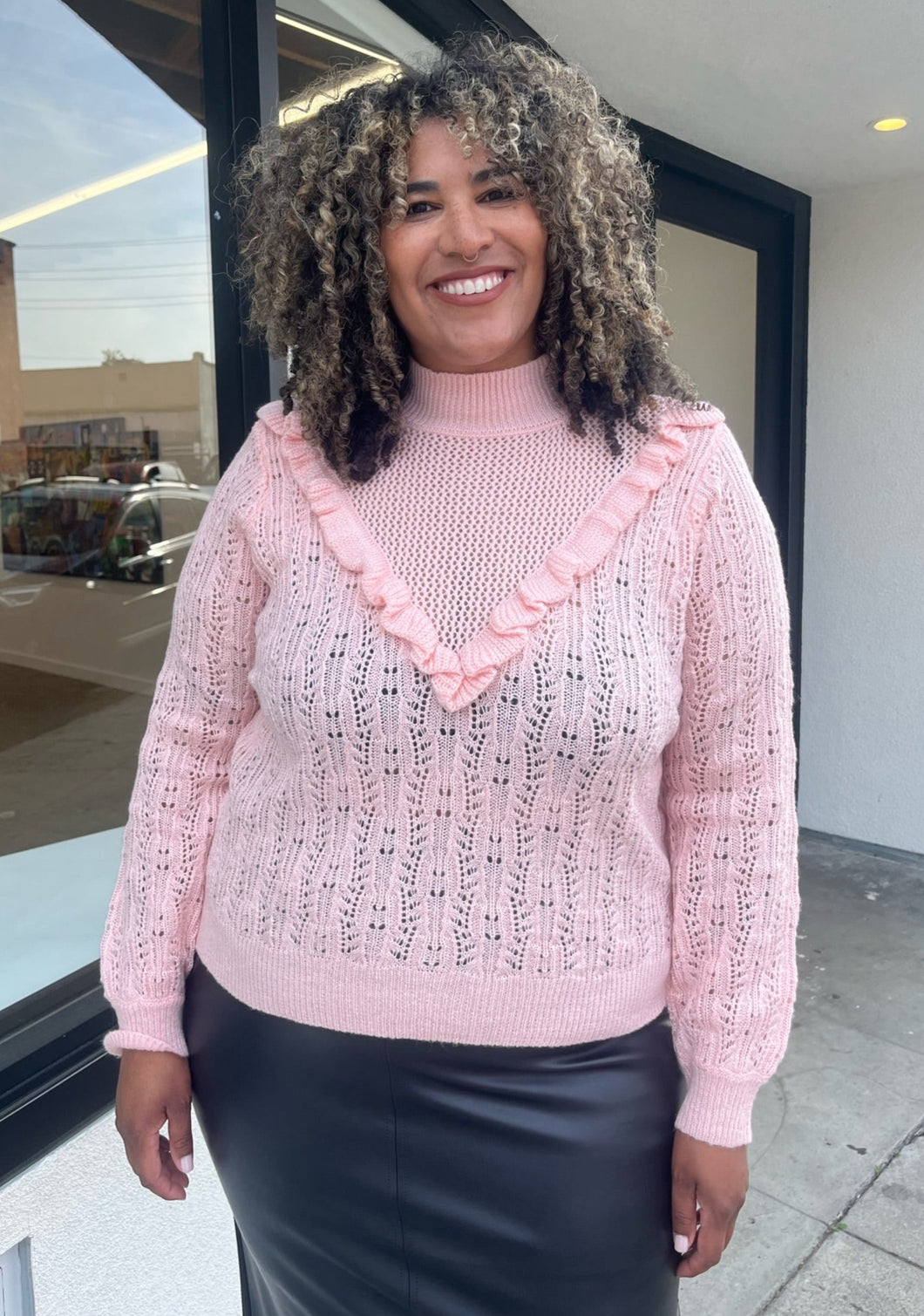 Front view of a soft pink Eloquii sweater in a size 18/20 on a size 16/18 model.