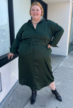 Load image into Gallery viewer, Full-body front view of a size 26 Eloquii emerald green maxi shirt dress with an o-ring fabric belt styled with black boots on a size 22/24 model. The photo is taken outside in natural lighting.
