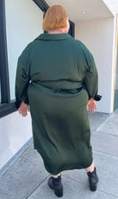 Load image into Gallery viewer, Full-body back view of a size 26 Eloquii emerald green maxi shirt dress with an o-ring fabric belt styled with black boots on a size 22/24 model. The photo is taken outside in natural lighting.
