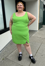 Load image into Gallery viewer, Additional full-body front view of a size 24 ASOS lime green mini sheath dress with a small slit at the hem styled with black mary janes on a size 22/24 model. The photo is taken outside in natural lighting.
