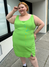 Load image into Gallery viewer, Front view of a size 24 ASOS lime green mini sheath dress with a small slit at the hem styled with black mary janes on a size 22/24 model. The photo is taken outside in natural lighting.
