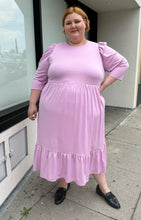Load image into Gallery viewer, Full-body front view of a size 2X Who What Wear light pink puff sleeve maxi dress with a ruffled hem styled with black slides on a size 22/24 model. The photo is taken outside in natural lighting.

