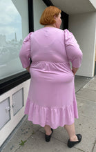 Load image into Gallery viewer, Full-body back view of a size 2X Who What Wear light pink puff sleeve maxi dress with a ruffled hem styled with black slides on a size 22/24 model. The photo is taken outside in natural lighting.
