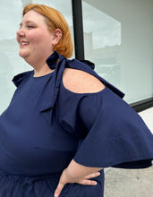 Load image into Gallery viewer, Close up view of the tie-detail cold shoulders of a size 22 Eloquii navy blue midi dress with ruffle details and tie-detail cold shoulders on a size 22/24 model. The photo is taken outside in natural lighting.
