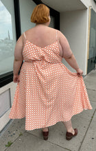 Load image into Gallery viewer, Full-body back view of a size 5X WRAY NYC orange and white checkered windowpane tank maxi dress with tie belt styled with brown mules on a size 22/24 model. The photo is taken outside in natural lighting.
