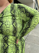 Load image into Gallery viewer, Close up view of the snakeskin pattern of a size 26 ASOS lime green and black snake patterned maxi with twist-front tie detail and long sleeves on a size 22/24 model. The photo is taken outside in natural lighting.
