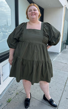 Load image into Gallery viewer, Additional full-body front view of a size 3X A New Day olive green square neck puff sleeve tiered dress styled with black slides on a size 22/24 model. The photo is taken outside in natural lighting.
