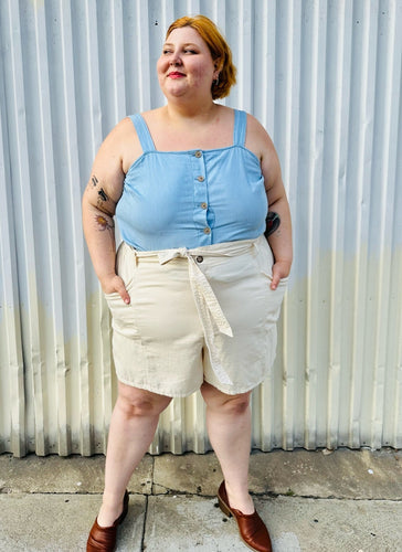 Full-body front view of a size 4X Old Navy cream khaki shorts with tie belt styled with a light blue tank tucked in and brown mules on a size 22/24 model. The photo is taken outside in natural lighting.