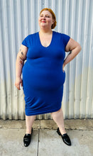 Load image into Gallery viewer, Additional full-body front view of a size M (Universal Standard size 18/20) royal blue v-neck t-shirt dress styled with black loafer slides on a size 22/24 model. The photo is taken outside in natural lighting.
