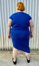 Load image into Gallery viewer, Full-body back view of a size M (Universal Standard size 18/20) royal blue v-neck t-shirt dress styled with black loafer slides on a size 22/24 model. The photo is taken outside in natural lighting.
