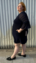 Load image into Gallery viewer, Full-body side view of a size 2X Nina Leonard navy blue mini dress with sheer mesh tiered sleeves styled with black slide loafers. The photo is taken outside in natural lighting.

