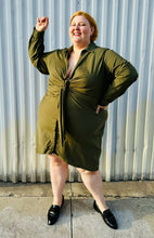 Load image into Gallery viewer, Full-body front view of a size 4 Fashion to Figure army green twist-front collared shirt dress styled with black slide loafers on a size 22/24 model. The photo is taken outside in natural lighting.
