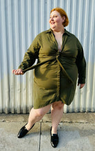 Load image into Gallery viewer, Full-body front view showing off the tie detail at the bust of a size 4 Fashion to Figure army green twist-front collared shirt dress styled with black slide loafers on a size 22/24 model. The photo is taken outside in natural lighting.
