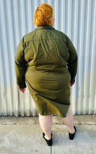 Load image into Gallery viewer, Full-body back view of a size 4 Fashion to Figure army green twist-front collared shirt dress styled with black slide loafers on a size 22/24 model. The photo is taken outside in natural lighting.
