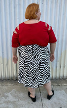 Load image into Gallery viewer, Full-body back view of a size 22 Novella black and white sequin zebra pattern maxi skirt with side slit styled with a red top and black loafer slides on a size 22/24 model. The photo is taken outside in natural lighting.
