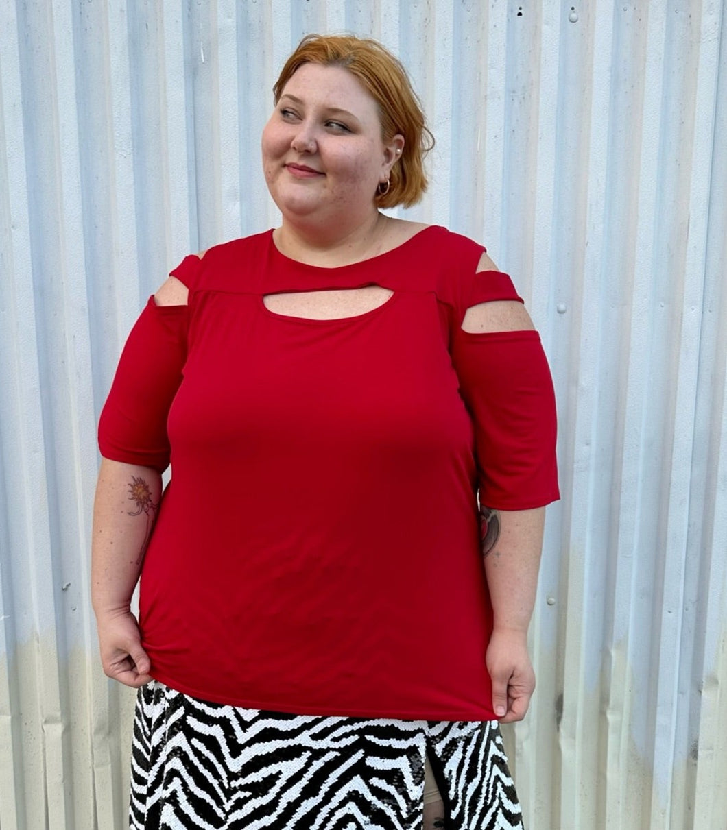 Front view of a size 30/32 Ashley Stewart red cut-out blouse with shoulder, sleeve, and bust cut-outs on a size 22/24 model. The photo is taken outside in natural lighting.