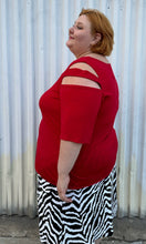 Load image into Gallery viewer, Side view of a size 30/32 Ashley Stewart red cut-out blouse with shoulder, sleeve, and bust cut-outs on a size 22/24 model. The photo is taken outside in natural lighting.
