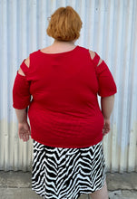 Load image into Gallery viewer, Back view of a size 30/32 Ashley Stewart red cut-out blouse with shoulder, sleeve, and bust cut-outs on a size 22/24 model. The photo is taken outside in natural lighting.

