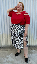 Load image into Gallery viewer, Full-body front view of a size 30/32 Ashley Stewart red cut-out blouse with shoulder, sleeve, and bust cut-outs styled tied into a knot over a sequin maxi skirt on a size 22/24 model. The photo is taken outside in natural lighting.
