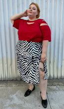Load image into Gallery viewer, Full-body front view of a size 22 Novella black and white sequin zebra pattern maxi skirt with side slit styled with a red top and black loafer slides on a size 22/24 model. The photo is taken outside in natural lighting.

