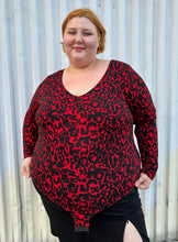 Load image into Gallery viewer, Front view of a size 22/24 Eloquii black and red leopard pattern long sleeve bodysuit on a size 22/24 model. The photo is taken outside in natural lighting.
