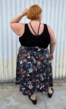 Load image into Gallery viewer, Full-body back view of a size 24 Eloquii black pleather maxi skirt with cool-toned floral all-over pattern styled with a black criss-cross tank tucked in and black loafers on a size 22/24 model. The photo is taken outside in natural lighitng.
