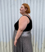 Load image into Gallery viewer, Side view of a size 2 Torrid black criss-cross detail stretchy bodysuit styled tucked into a silver sequin maxi skirt on a size 22/24 model. The photo is taken outside in natural lighting.
