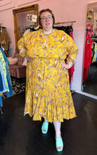 Load image into Gallery viewer, Full-body front view of a size 4X H&amp;M x Johanna Ortiz golden yellow, white, and brown mixed pattern of birds in trees maxi dress with keyhole neckline and back, ruffle hem, and ruffles cuffs styled with pastel teal mules on a size 24 model. The photo was taken inside under flourescent and natural lighting.
