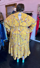 Load image into Gallery viewer, Full-body back view of a size 4X H&amp;M x Johanna Ortiz golden yellow, white, and brown mixed pattern of birds in trees maxi dress with keyhole neckline and back, ruffle hem, and ruffles cuffs styled with pastel teal mules on a size 24 model. The photo was taken inside under flourescent and natural lighting.
