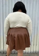 Load image into Gallery viewer, Back view of a size 18/20 Eloquii cream chunky knit sweater with swiss dots styled tucked into a brown pleather mini skirt on a size 18/20 model. The photo is taken outside in natural lighting.

