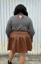 Load image into Gallery viewer, Back view showing off the keyhole back detail of a size 20 Eloquii black and white patterned sweater with choker neckline and puff sleeves styled over a brown pleather mini skirt on a size 18/20 model. The photo is taken outside in natural lighting.
