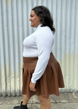 Load image into Gallery viewer, Side view of a size 18/20 Eloquii black and white halfsies long sleeve tee styled tucked into a brown pleather mini skirt on a size 18/20 model. The photo is taken outside in natural lighting.
