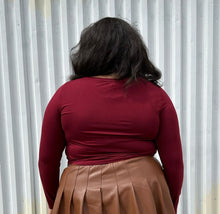Load image into Gallery viewer, Back view of a size 18/20 maroon long sleeve cropped t-shirt styled over a brown pleather mini skirt on a size 18/20 model. The photo is taken outside in natural lighting.
