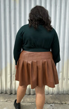 Load image into Gallery viewer, Back view of a size 18/20 Eloquii dark green longline sweater with side slits, a tie belt, subtle puff sleeves, and a v neck styled tucked into a brown pleather mini skirt on a size 18/20 model. The photo is taken outside in natural lighting.
