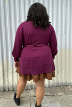 Load image into Gallery viewer, Back view of a size 18/20 Eloquii berry pink longline sweater with side slits, a tie belt, subtle puff sleeves, and a v neck styled over a brown pleather mini skirt on a size 18/20 model. The photo is taken outside in natural lighting.
