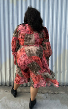 Load image into Gallery viewer, Full-body back view of a 18 Rachel Parcell pink, coral, brown, and cream patchwork floral pattern with pleated skirt, pussy bow, and bishop sleeve styled with black boots on a size 18/20 model. The photo is taken outside in natural lighting.
