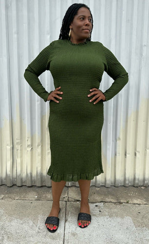 Full-body front view of a size XXL Rachel Parcell forest green all-over smocking long sleeve midi dress with mock neckline and ruffle hem styled with black slides on a size 14/16 model. The photo is taken outside in natural lighting.
